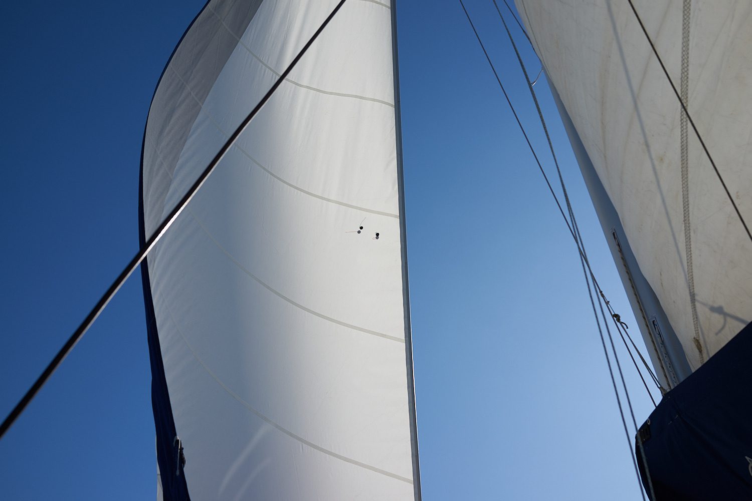A sail is shown against the blue sky.