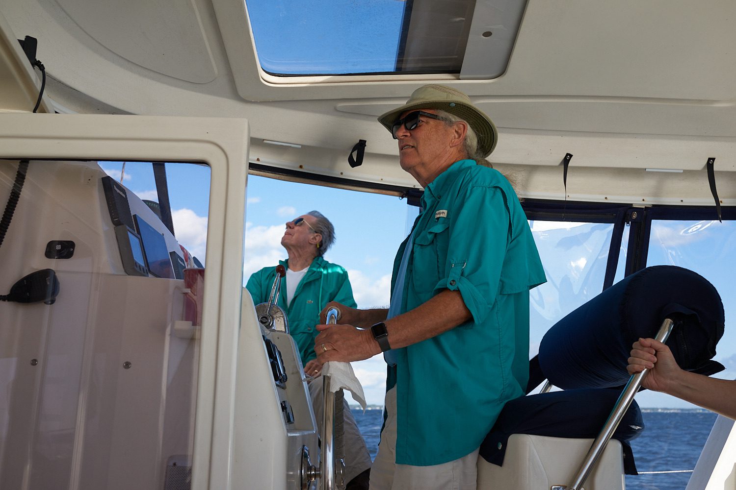 Two men in green shirts and hats on a boat.