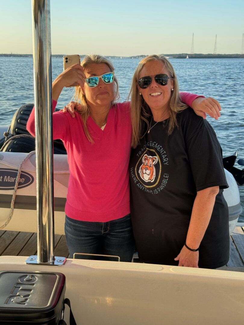 Two women posing for a picture on the deck of a boat.