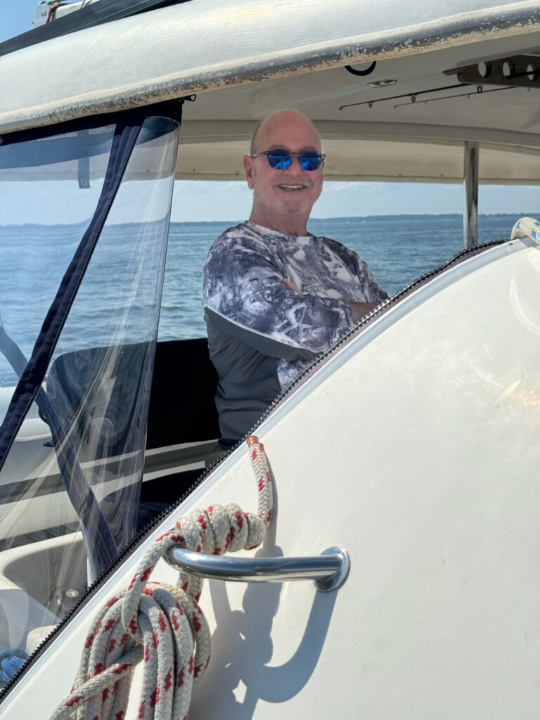 A man in sunglasses sitting on the front of a boat.