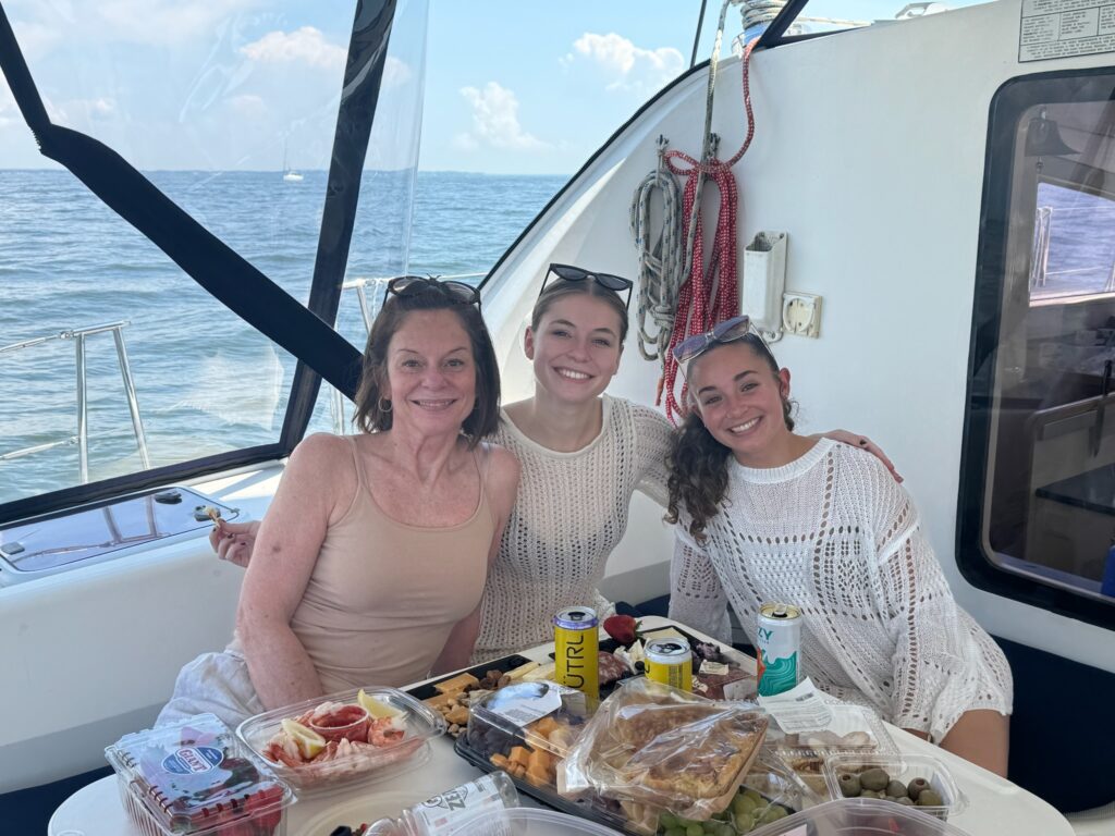 Three women sitting at a table with food on it.